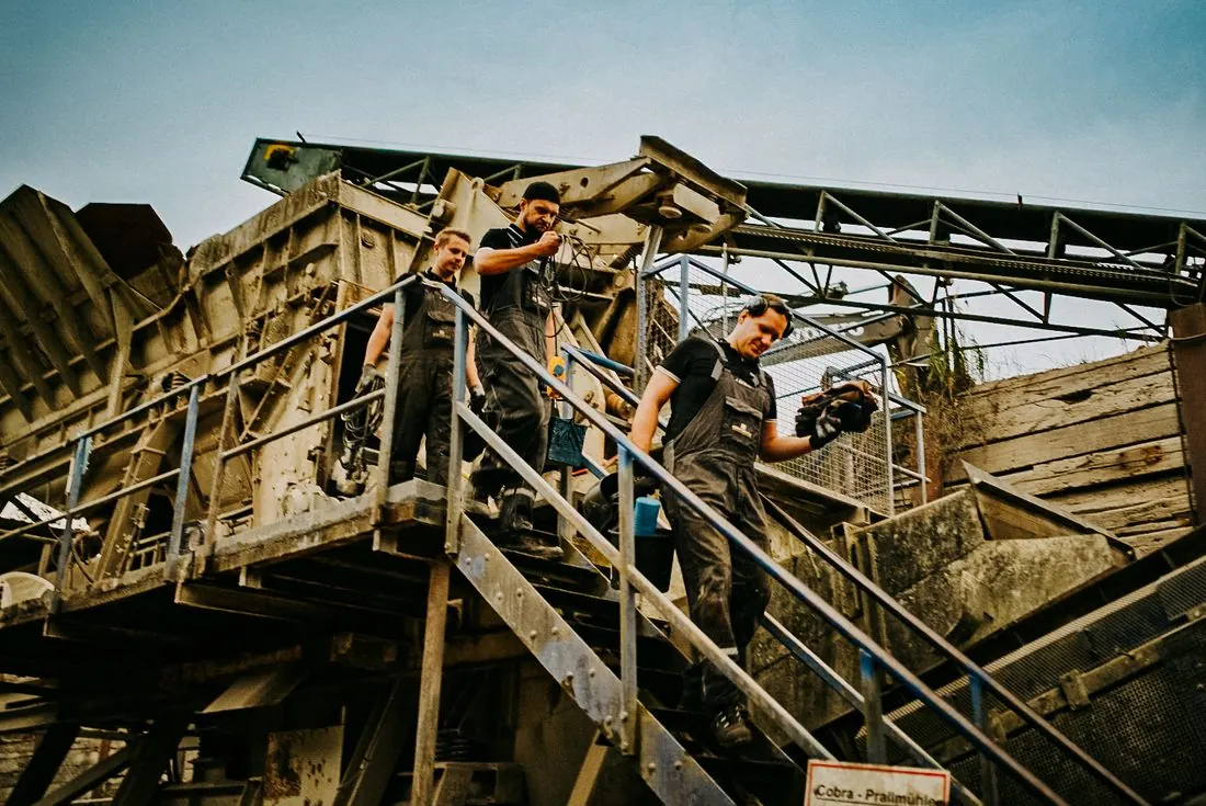 Monteure auf der Treppe einer Brechanlage